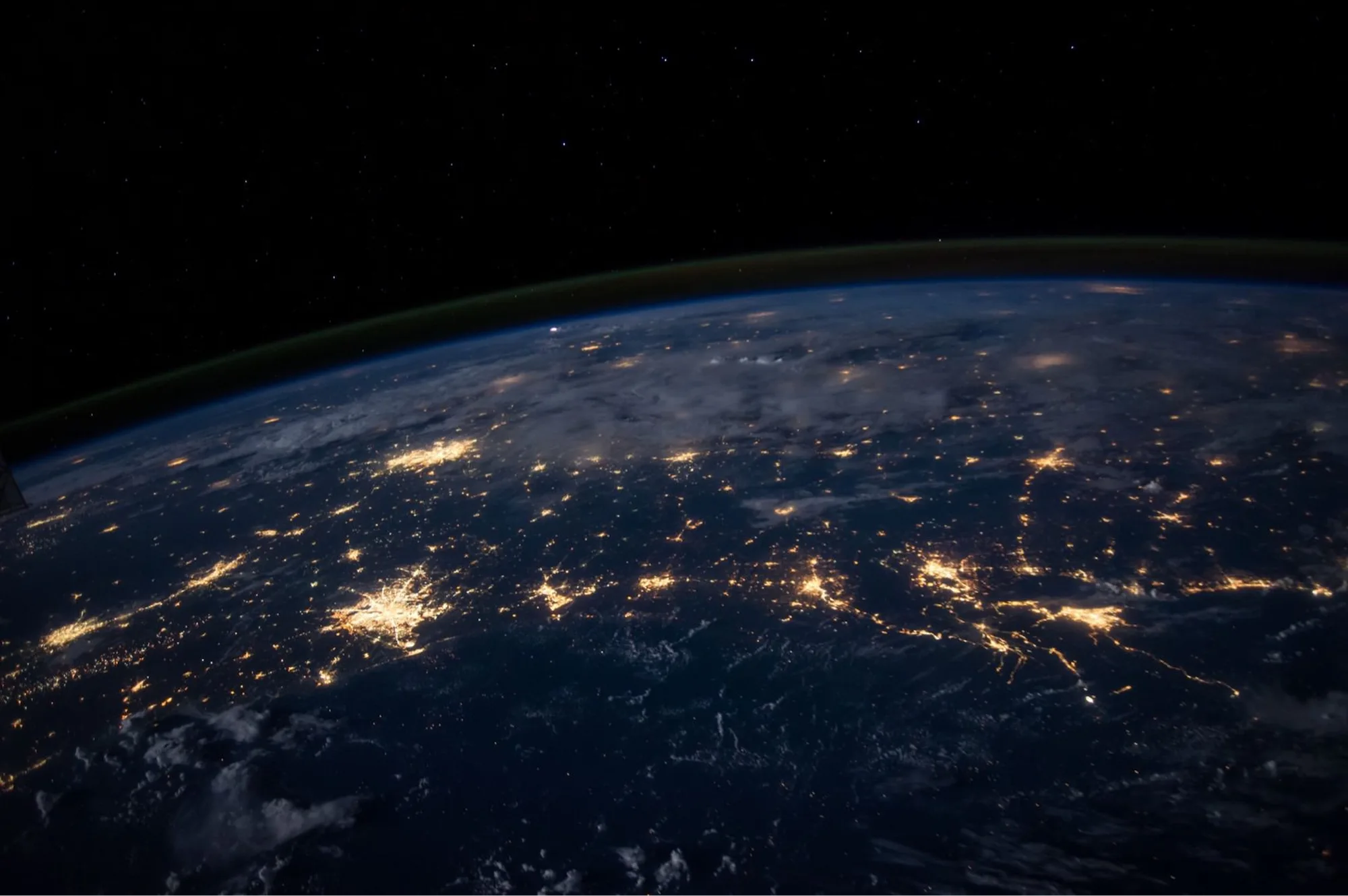 Earth at night from space, showing city lights and the curve of the planet.